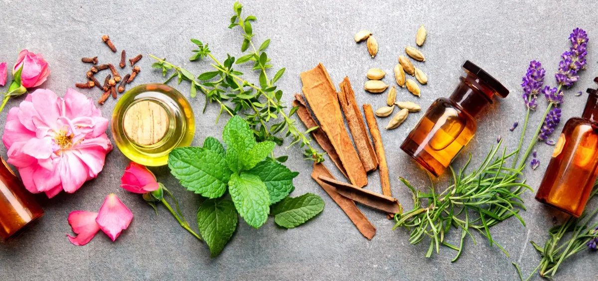 Amber glass bottles with fresh botanicals — rose, mint, cinnamon, cardamom and lavender