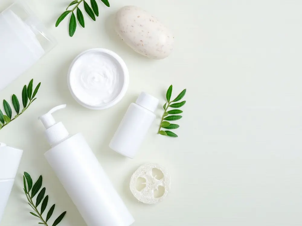White finished-product bottles, a jar and soap staged with olive branches