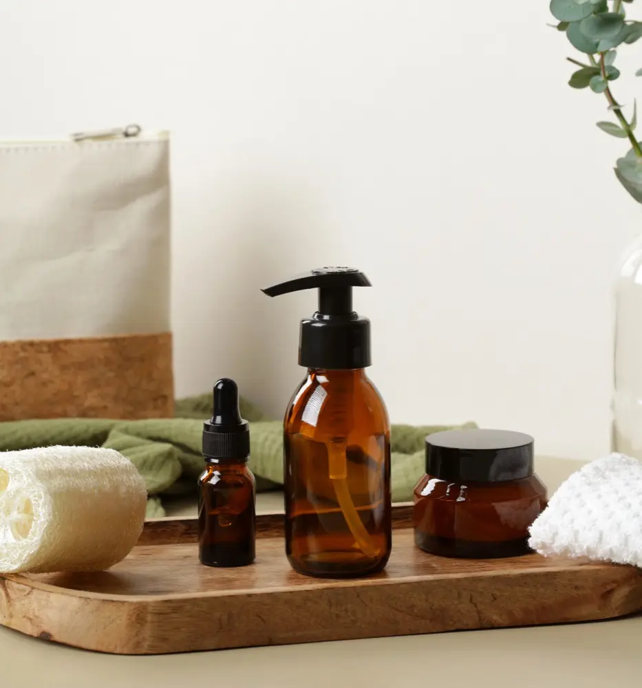Amber glass bottles and jars, a loofah and a eucalyptus sprig staged on a wooden tray